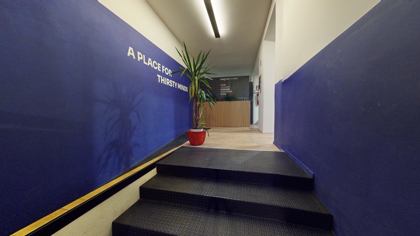 Ingresso di uno spazio di coworking con pareti blu e la scritta A place for thirsty minds